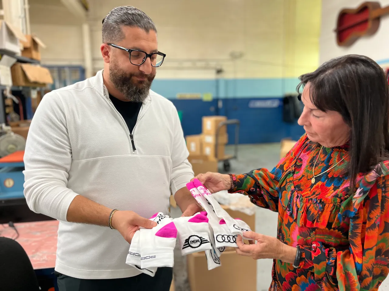 Karen MacDonald, right, founder of Wrapped in Love looks at a sampling of socks presented by Laba Soyad, co-owner of Soyad Brothers Textile Corporation in Fraser. (Gina Joseph - The Macomb Daily)
